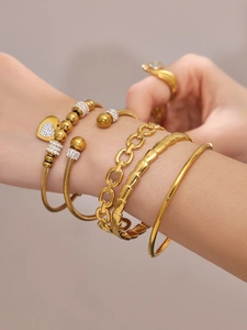 Detalle de una modelo luciendo un conjunto de cinco pulseras doradas minimalistas
