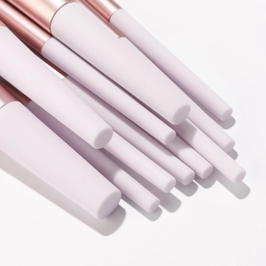 Détail des manches de pinceaux de maquillage lilas mat avec viroles en métal or rose