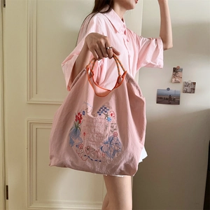 Détail du sac cabas rose en Oxford avec broderie florale et anses rayées
