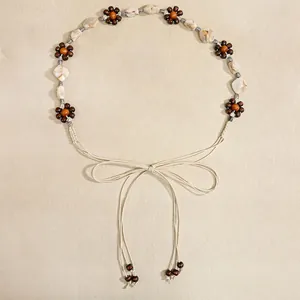 Detail of bohemian woven belt with wooden beads, floral accents and tassel fringe