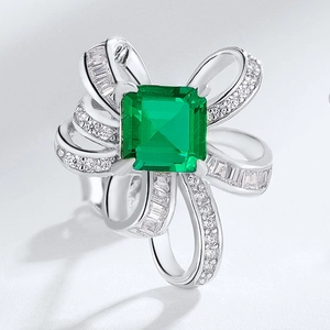 Elegant silver ring with emerald-cut green stone in a bow-shaped diamond setting