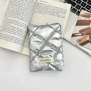 Detailed view of silver metallic quilted passport holder with brand tag on desktop
