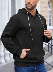 Close-up detail of herringbone texture on black hoodie with buttoned neckline