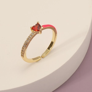 Detailed close-up of golden heart ring featuring red gemstone, pink enamel and zircons