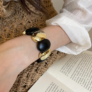 Detail of chunky acrylic stretch bracelet with matte black and gold oval links
