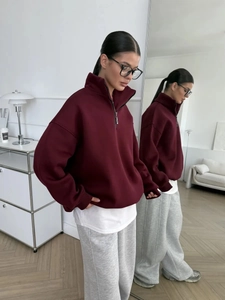 Detail of maroon half-zip sweatshirt with a relaxed fit and thick fleece texture