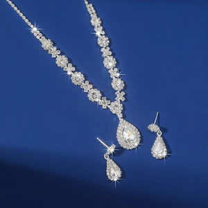 Detail of silver drop-shaped crystal pendant necklace and earrings on dark background