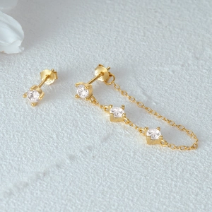 Macro shot of gold S925 sterling silver four-prong diamond stud with tassel chain earring