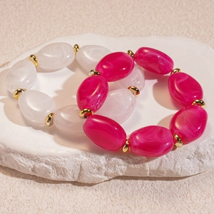 Macro detail of acrylic marble oval bead bracelets with gold metal spacers on stone base