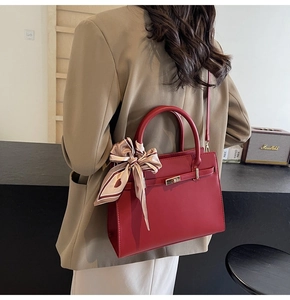 Detail view of red fashion handbag with heart-pattern scarf and metallic buckle