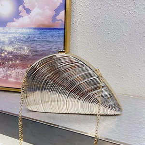 Detail of silver shell-shaped evening clutch bag with gold clasp and chain strap