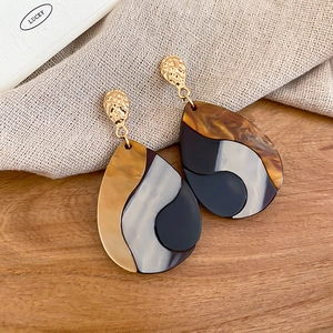 Detail view of water-drop earrings featuring gold hammered metal and amber marble resin