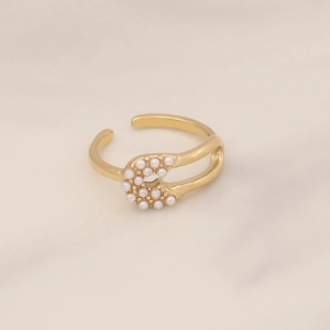 Detailed view of a gold safety pin open ring with small pearls on white marble background