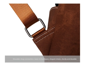 Detail of reinforced shoulder strap connection with silver metal ring on brown backpack