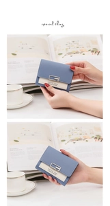Close-up of a mini bifold wallet in blue and beige faux leather with a silver square clasp