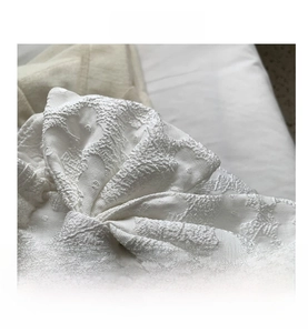 Close-up of creamy white jacquard fabric bow showing detailed embossed texture and craftsmanship
