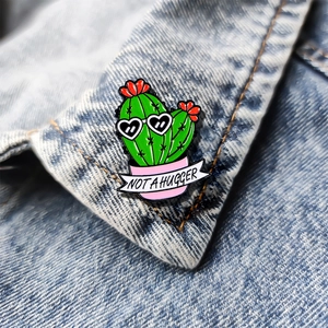 Cute cactus enamel pin with 'NOT A HUGGER' text on blue denim jacket collar