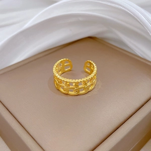 Detail eines goldenen Gliederkettenrings mit B-Motiv auf einem braunen Leder-Schmuckständer