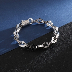 Gros plan détaillé du bracelet en acier argenté à maillons croisés creux et fermoir cylindre