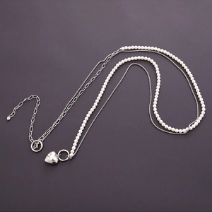 Detail of double-layer chain with silver metal, white pearls, and heart charm toggle