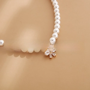 Macro detail of 18k gold plated bow pendant with cubic zirconia on a pearl necklace
