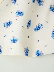 Close-up of blue floral print on white blazer fabric with detailed textile texture