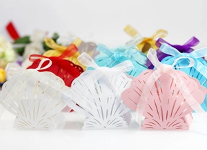 Detailed laser-cut seashell favor boxes with silk ribbon bows in multiple soft colors