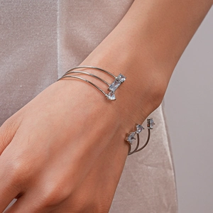 Détail du bracelet ouvert en argent avec zircons sur poignet contre velours violet