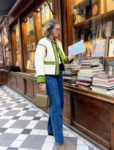 Detail of color-block quilted jacket with green trim and utility pockets in a bookstore