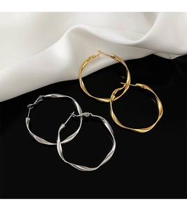 Detailed view of twisted geometric hoop earrings in polished gold and silver finishes