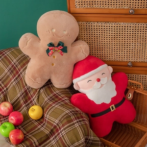 Close-up of plush gingerbread man and Santa Claus festive Christmas cushions on a cozy blanket