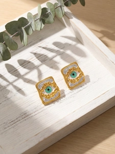Macro detail of square evil eye earrings with enamel inlay and pavé stones on white wood