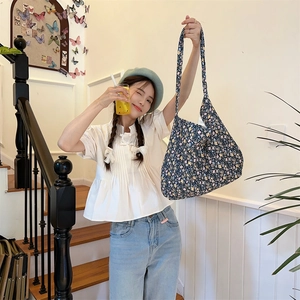 Close-up of a floral pattern shoulder bag with long straps worn in a lifestyle setting