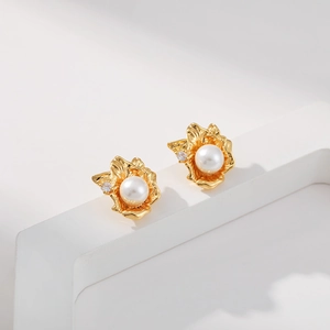 Detailed close-up of geometric gold petal earrings with white pearl and zircon accents