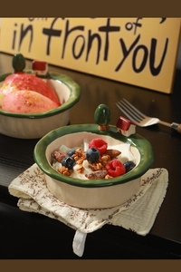 Detail of hand-painted ceramic bowl with 3D house ornament and fresh fruit yogurt