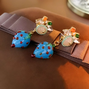 Detailed close-up of blue strawberry earrings with crystals on a vintage gift box