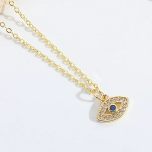 Macro shot of gold Evil Eye necklace featuring blue gemstone and pavé zircon details