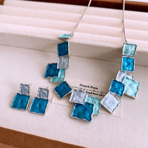 Detailed shot of vintage blue square enamel necklace and earrings set in a jewelry box