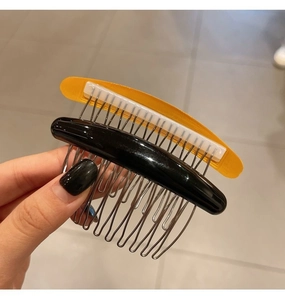 Close-up of black and amber non-slip hair side combs with metal teeth for styling