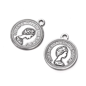 Detailed macro view of two antique silver coin pendants featuring Queen Elizabeth II relief