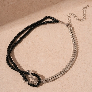 Detail of knotted double-layer necklace with black beads and rhinestone-pave silver chain