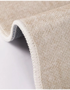 Detailed macro view of the beige plush rug showing high-quality edge stitching and texture