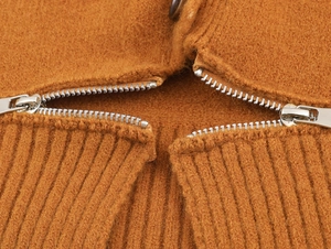 Détail d'un manteau en laine caramel avec fermeture éclair métallique et texture tricotée