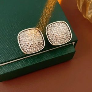 Close-up of square pavé stud earrings with cubic zirconia on a green leather box