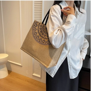 Brown linen tote bag with black bohemian patterns worn on a woman's shoulder
