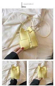 Detail of yellow woven bucket bag with drawstring closure and slim shoulder strap