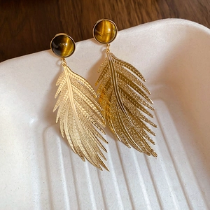 Close-up of vintage golden leaf earrings featuring circular tiger eye stone inlay