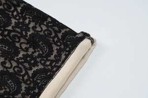 Close-up of black floral lace stitching with beige lining on elegant backless jumpsuit