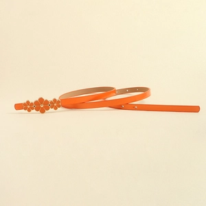 Detail showing orange PU leather skinny belt with three gold-trimmed flower buckles