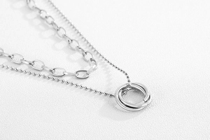 Macro shot of silver layered necklace with interlocked rings and paperclip chain detail